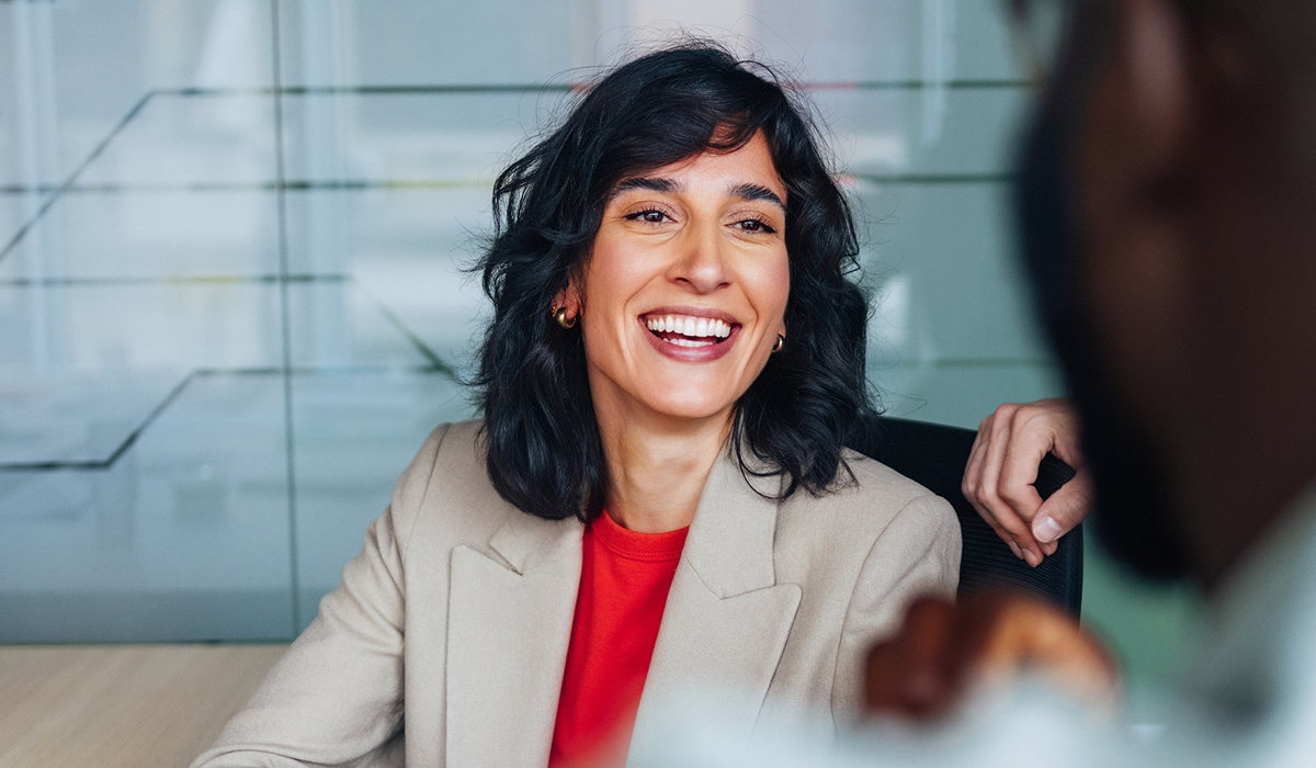 Professionista sorride mentre partecipa a una riunione con il team.